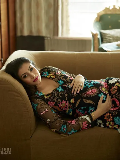 Another perspective from the same maternity shoot, showing a wider angle of the pose. This composition highlights the beautiful drape of the dress and creates a relaxed, reclining portrait that feels both glamorous and natural.
