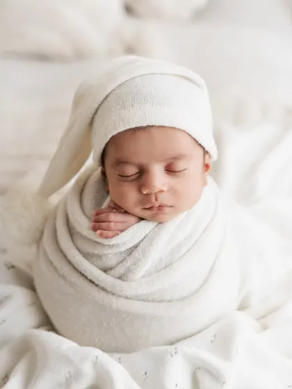Another angle of this peaceful baby in an all-white setup. The soft lighting and textures create a dreamy, angelic feel for this classic newborn photo.