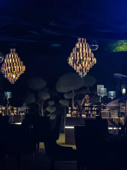 An atmospheric shot of a Diwali celebration, with magnificent crystal chandeliers hanging from the trees, casting a luxurious glow over the evening.