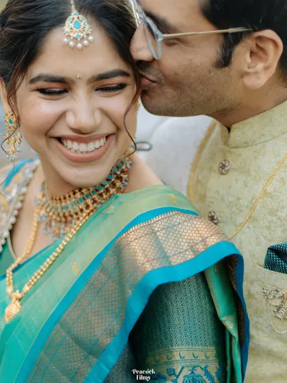 A sweet and candid moment, with the groom giving the bride a gentle kiss on the cheek, her joyful smile says it all.