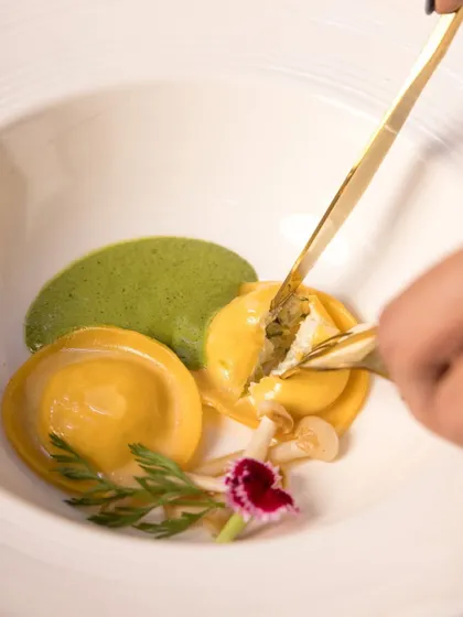 A delicate moment with our Truffle Fungi Cream Cheese Ravioli, part of the Holiday Feast. The filling is revealed, showcasing the rich, creamy texture inside.