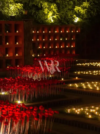 A garden of red and warmth. This installation features fields of red poppies and beds of candles, with a candle wall in the background, creating a mesmerizing and soulful landscape.