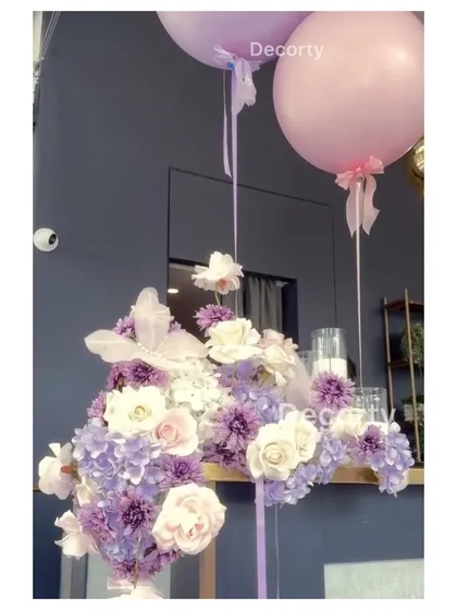 An elegant floral arrangement used as a centerpiece, with large balloons adding a touch of celebratory fun.