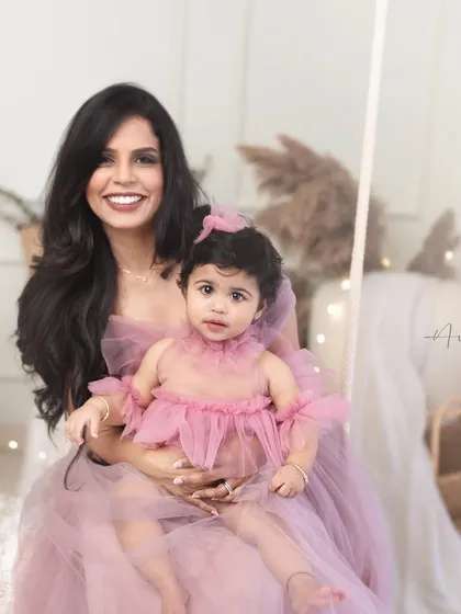 A joyful mother and daughter portrait, celebrating a first birthday. Their coordinated outfits and bright smiles make this a perfect celebratory image.