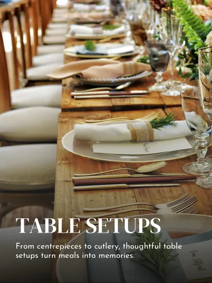 Thoughtful table setups turn meals into memories. This long table arrangement with rustic placemats, elegant cutlery, and fresh rosemary sprigs creates a warm and inviting atmosphere for a sit down dinner.