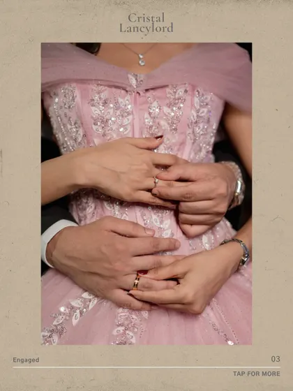 A close-up on the couple's hands and rings, showing the detail of the bride's embroidered pink dress.