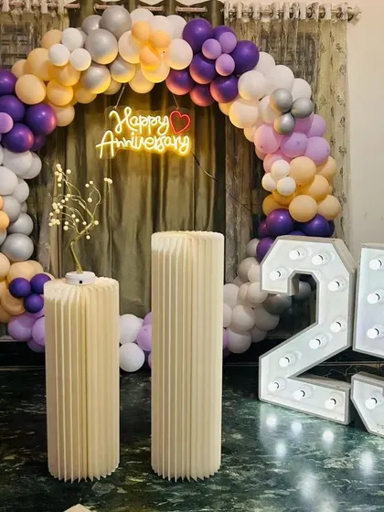 A simple and elegant anniversary setup with a pastel balloon arch and light-up '25' numbers, perfect for an intimate celebration.