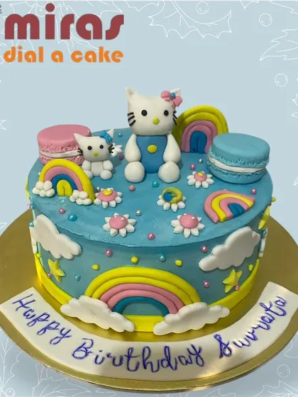 A whimsical Hello Kitty cake set in a sky-blue world of rainbows and clouds. Featuring Hello Kitty and a friend, this cake is adorned with colorful macarons for an extra sweet touch.