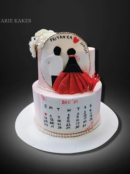 This custom wedding cake design features a calendar marking the special day. The top tier includes a silhouette of the couple and a flowing red dress detail made from fondant.