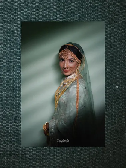 A moody and artistic portrait of a bride, with dramatic lighting creating shadows that highlight her features and jewelry.