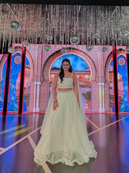 A full view of my white lehenga against the grand LED screen, which displayed a beautiful palace arch, enhancing the royal theme of the Sangeet.