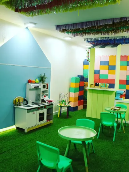 A wide view of our pretend play area, featuring a kitchenette, tables, and giant building blocks for endless creative fun.