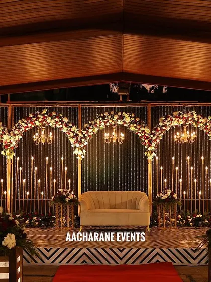 This is an elegant outdoor reception stage setup. I used a series of arches decorated with red and white flowers, with beautiful chandeliers and candle stands providing warm, romantic lighting for the evening.