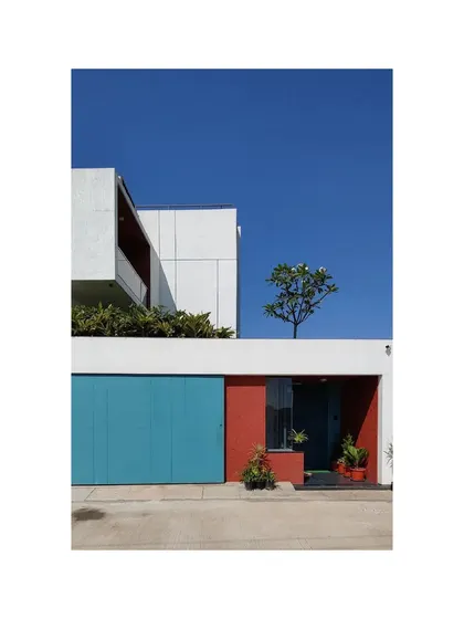 The entrance to the Notan Home is marked by a bold use of color, with a bright blue garage door and a warm red accent wall. This playful introduction sets the tone for a home that is filled with surprising and joyful design moments.