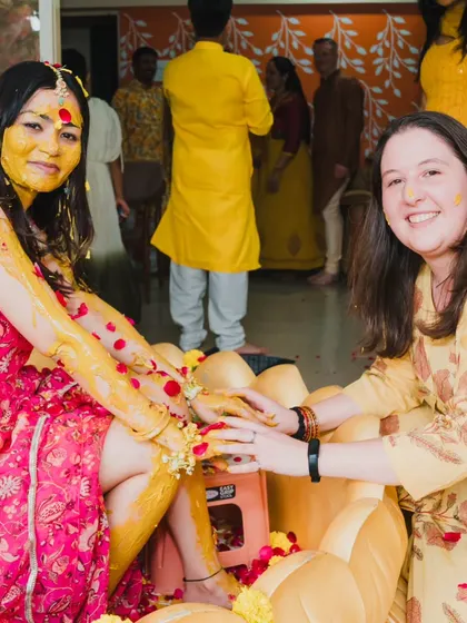 A candid shot of two friends sharing a laugh while applying Haldi, showcasing the fun and relaxed atmosphere of the event.