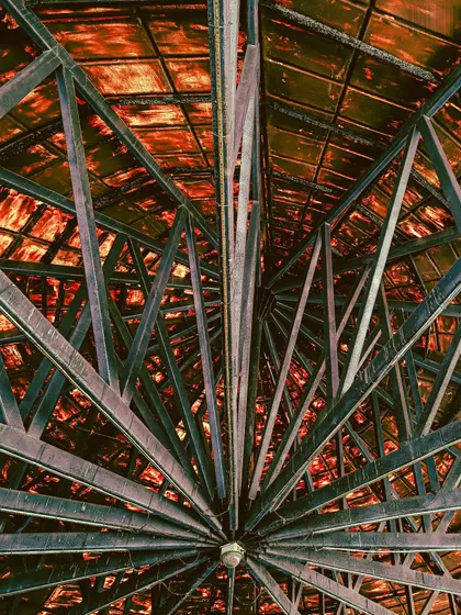 Looking up into the metal framework of a roof. This abstract shot turns a structural element into a piece of art, focusing on symmetry and lines.