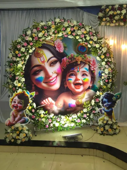 A detailed look at the custom printed backdrop for the Krishna-themed baby shower, surrounded by a thick floral wreath.