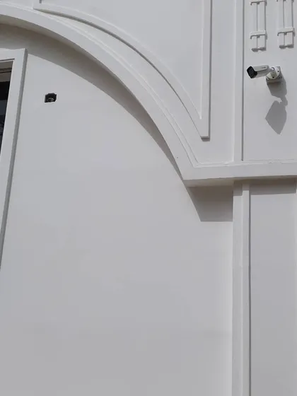A wider shot of the camera near the window and gate, showing how it fits into the building's architecture.