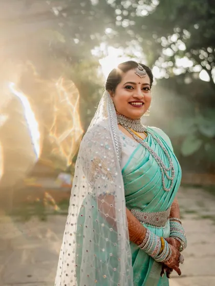 A sun-kissed bride in her beautiful turquoise saree. The natural light and lush green background make for a fresh and vibrant bridal portrait.