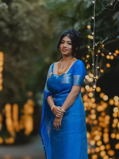 A full-length shot of the bride against a backdrop of fairy lights. The blue of her saree and her glowing makeup create a magical look.