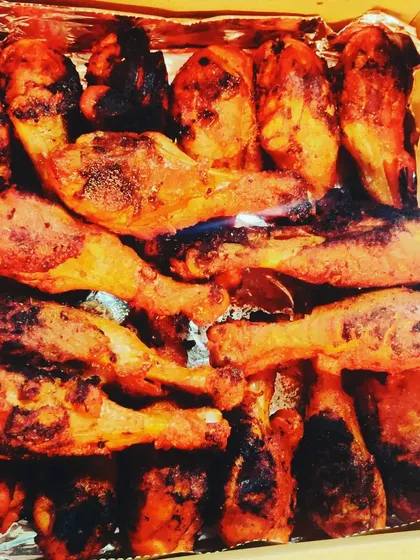 A takeaway box filled with our perfectly grilled chicken legs. The char marks from the grill add a smoky depth of flavor that our clients love.