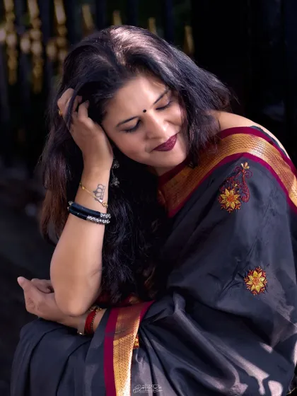 A pensive moment captured in the black and red saree. The rich colors and embroidery create a look full of depth and emotion.