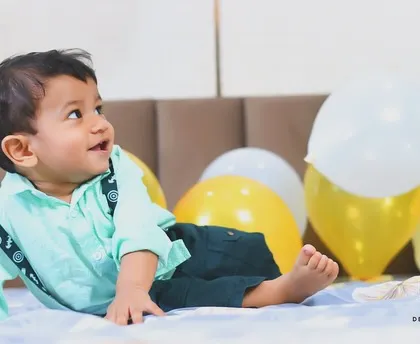 A happy baby boy enjoying his birthday balloons. This relaxed, at-home setting allows for natural expressions and comfortable, happy photos.