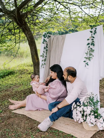 A family with their three-month-old baby, enjoying a picnic setup outdoors. It's amazing to see how quickly they grow.