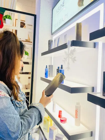 A client browsing our retail section, filled with premium products from brands like PH Laboratories and Keune, to continue her hair care at home.