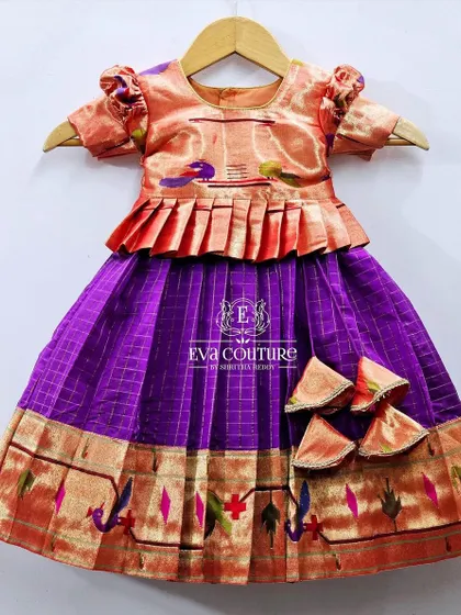 A pure Paithani handloom silk lehenga for little girls. The peach peplum top and purple checked skirt are both accented with authentic woven Paithani borders.