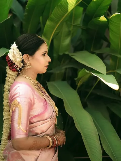 A side profile of the bride, highlighting her traditional gajra (floral hair adornment) and elegant posture.
