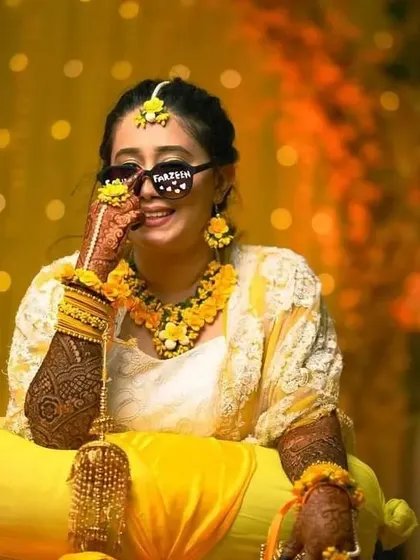 A fun and stylish bride at her haldi ceremony, rocking cool sunglasses and our full-arm bridal mehndi.
