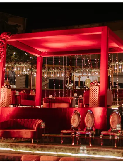 A luxurious red velvet seating area for a reception. The elegant canopy and cascading fairy lights provided a regal and intimate space for the couple and their close family.