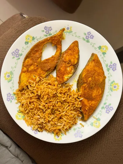A delicious dinner of tomato rice served with three pieces of pan-fried fish.