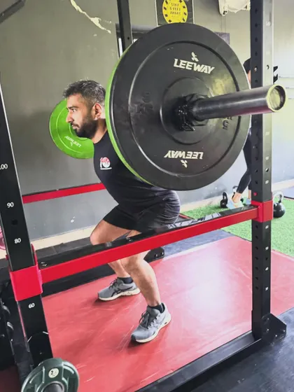 A client maintains a strong, upright posture during a heavy barbell squat. Our coaches ensure proper form to protect the spine and maximize leg development.