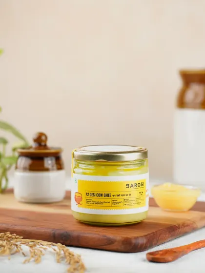 A clean and bright product shot of Barosi's A2 Desi Cow Ghee. The styling with traditional Indian pottery gives it an authentic, farm-fresh feel.