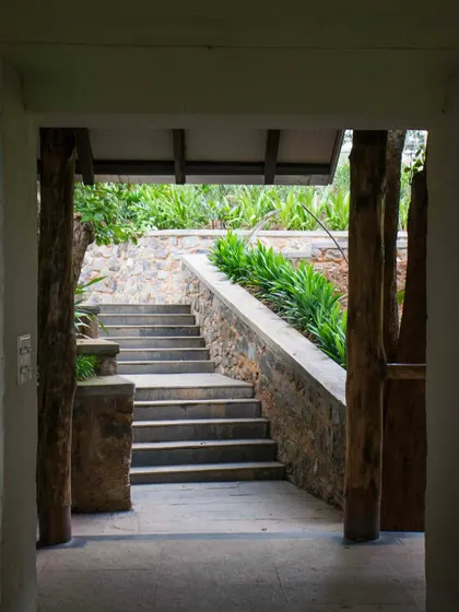 A view through a doorway at PLENTI House, looking out onto a flight of stone steps that navigate the steep terrain.