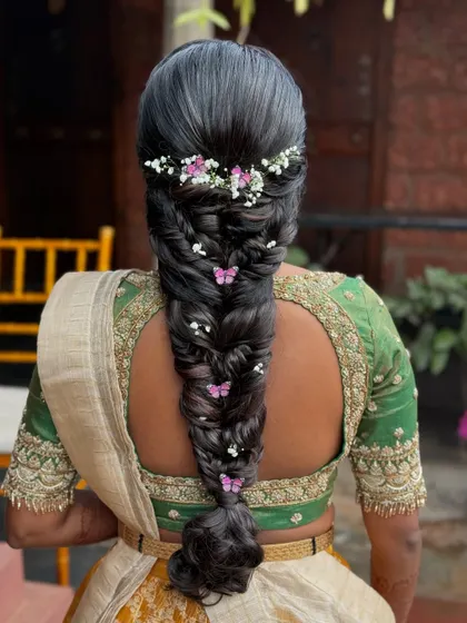The butterfly braid captured outdoors, with natural light highlighting the delicate accessories and the rich texture of the hair.