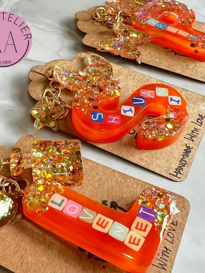 A collection of custom initial keychains, each with its own unique charm and glitter. They make for a perfect, personal accessory.
