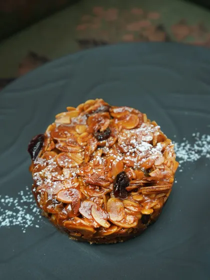 A close-up of our almond and fruit halwa tart, showing the rich texture of the caramelized nuts and dried fruit. It's a dessert that is both comforting and sophisticated.