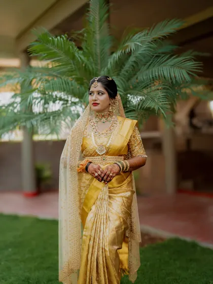 A portrait of the bride in a gorgeous yellow saree, her expression one of quiet elegance.