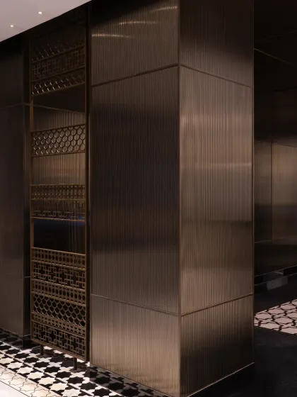 We integrated elements of Nepalese craftsmanship throughout the Soaltee lobby. These decorative metal screens feature intricate patterns inspired by traditional motifs, set within a contemporary framework of brushed bronze panels that define the space.