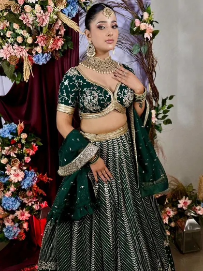 Another beautiful shot of the model in the deep green lehenga, set against a floral backdrop.