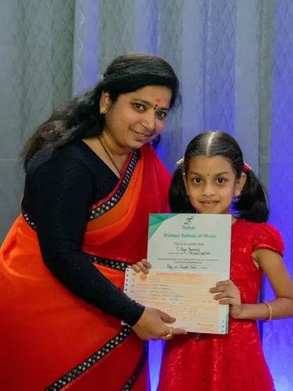 A young student proudly holds her music exam certificate. I provide a clear pathway for students to achieve internationally recognized qualifications.