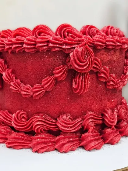 Another angle of the vibrant red vintage cake, showing the detailed piping work that covers the entire surface. This design is all about texture and bold color.