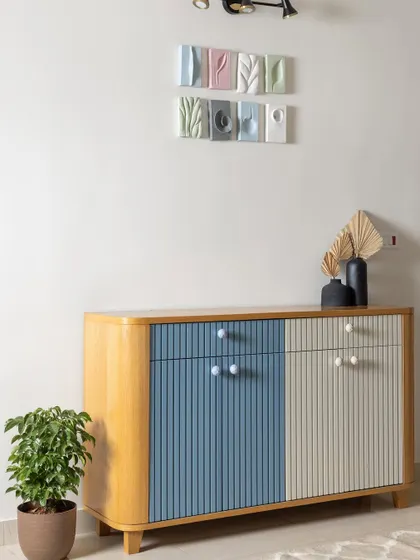This custom fluted crockery unit, painted in pastel blue and ivory, adds elegant charm to the dining space. Above it, custom ceramic artwork ties together the home's overall pastel theme.