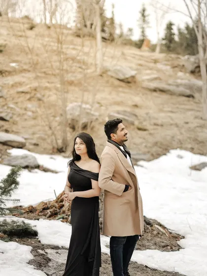 A stylish pose of a couple standing back-to-back against a snowy, barren landscape in Manali.