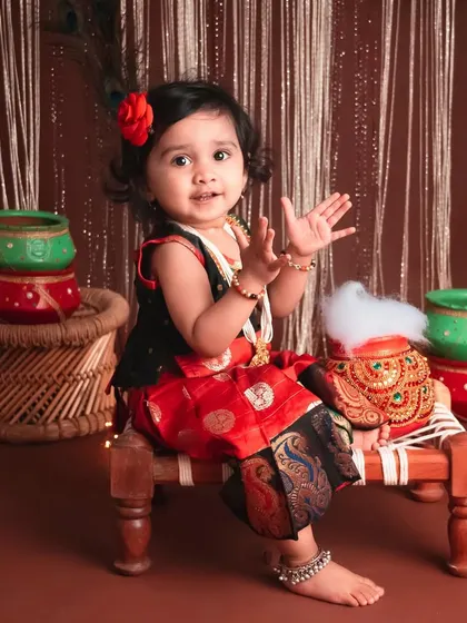 Clapping her hands with joy! This is another adorable moment from the same traditional photoshoot, showing her playful and happy spirit.