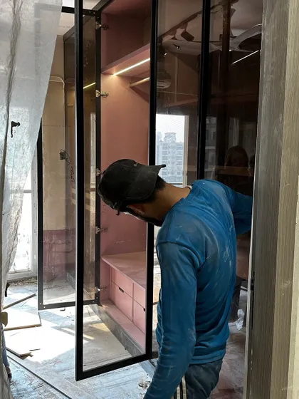 A behind-the-scenes shot of our team installing the custom pink and black glass wardrobe for a client's walk-in closet.