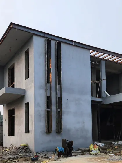 A wider view of the same house, showing the raw structure in its environment before landscaping and final exterior finishes are applied.